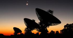 Radio telescope array pointed at sky with sunset behind